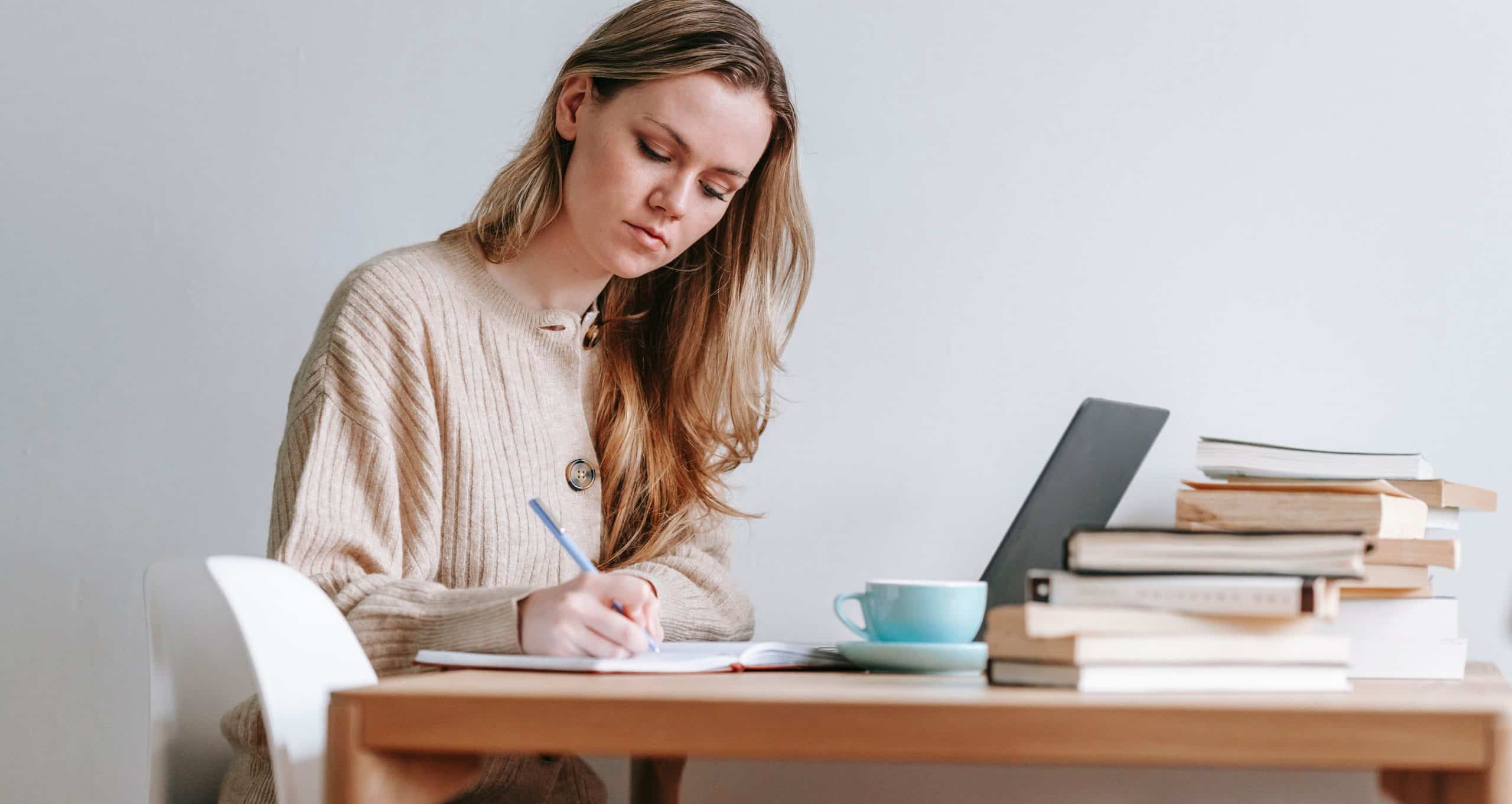 Student preparing for the IC&RC ADC exam review with study notes, books, and a laptop for CASAC exam prep and addiction counselor certification.